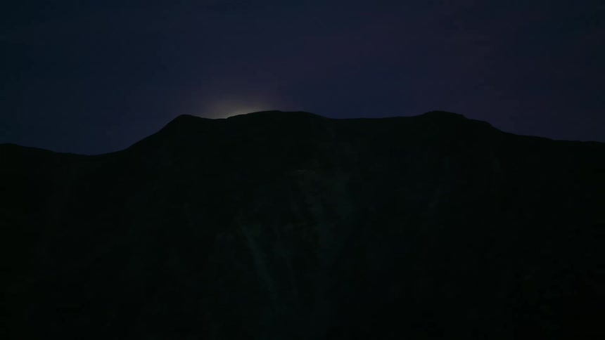 Aerial view of full moon behind the mountains at night