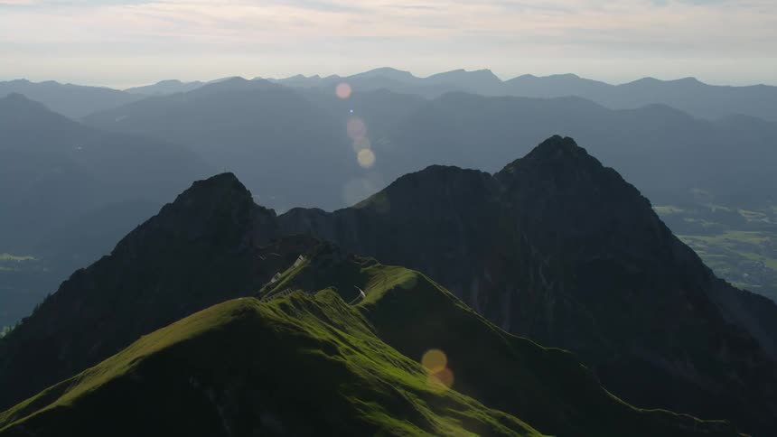 Aerial view of sunlight washing over the green slopes of a mountain