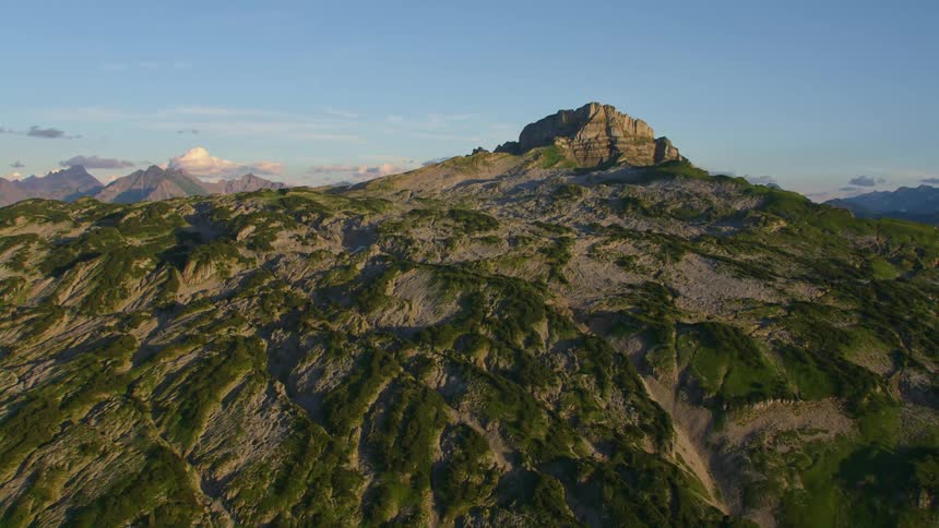Aerial view of the rugged slopes and peak of a mountain at evening