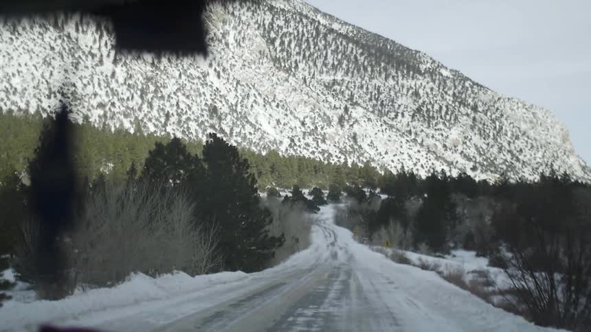 A vehicle is moving down an ice covered road toward a mountain