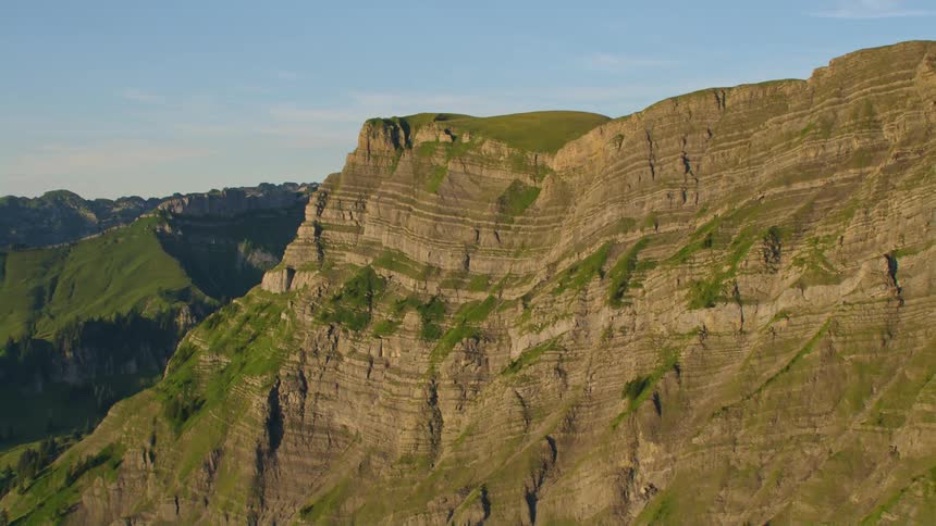 Vegetation covered covered mountains stretch to the horizon under a cloudy sky