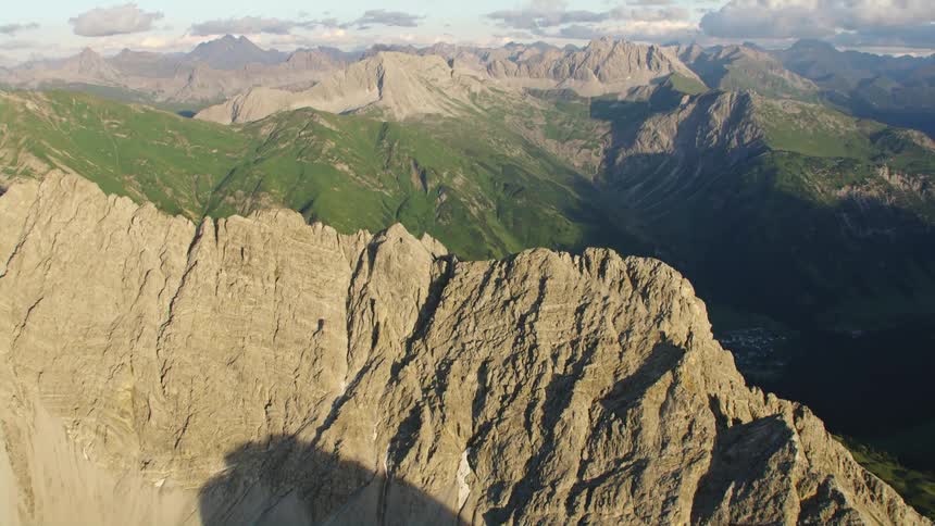 A mountain range with rocky peaks and slopes covered in low vegetation during the day