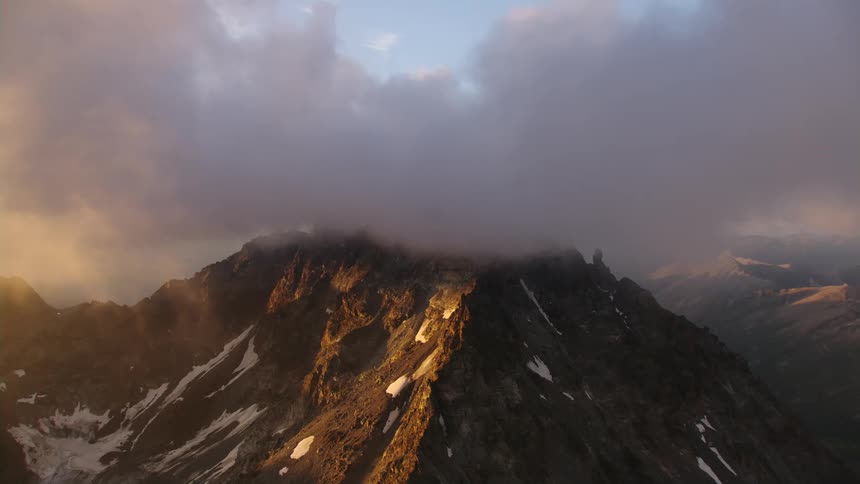 Aerial view of a tall mountain top covered in clouds at morning