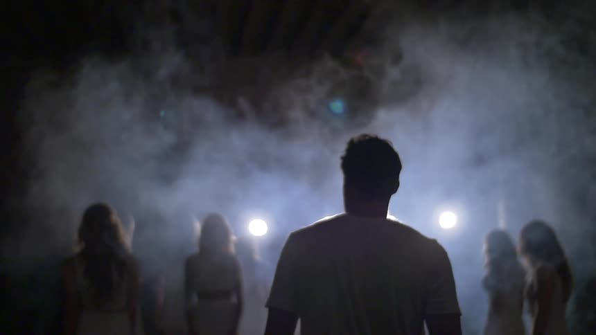 A man walks towards a group of women surrounded by fog