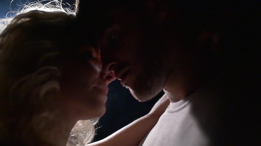A man and women get close in a dark area