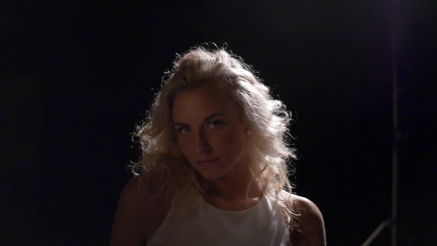 A woman turns her head forward in a dark area