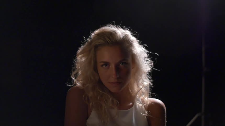 A woman with blonde hair shrugs one shoulder
