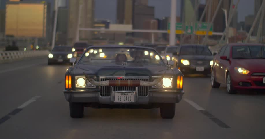 A car with horns on the front end passes many cars in traffic