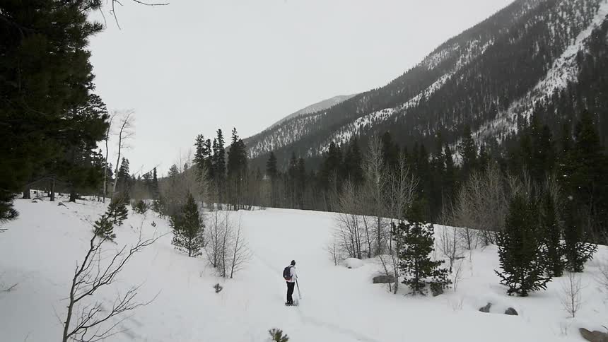 A person is standing in the snow before a mountain