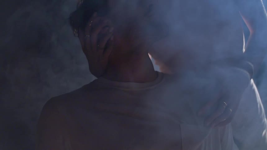 A woman is touching a man surrounded by smoke