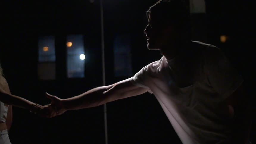 A woman pulls a man off in a dark room