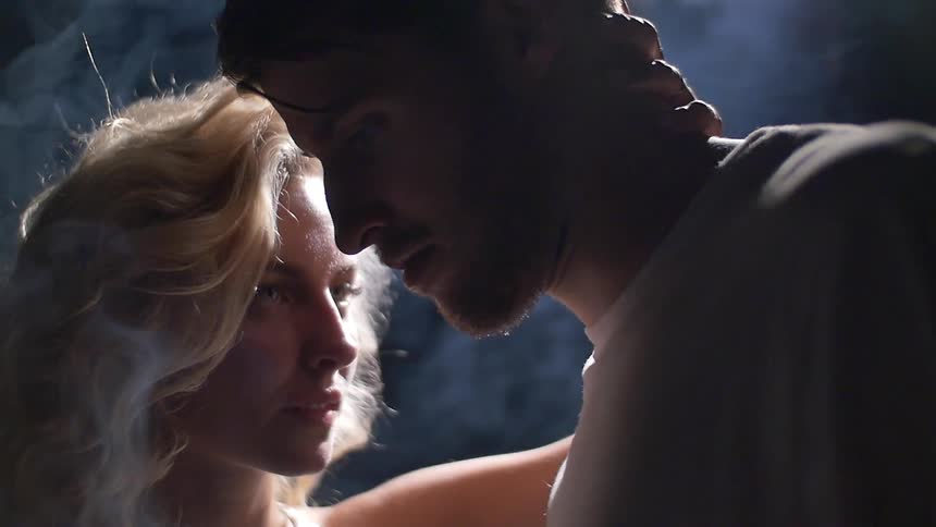 A man faces a woman as she touches his neck