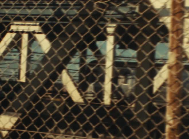 Passenger trains meet along tracks behind a fence