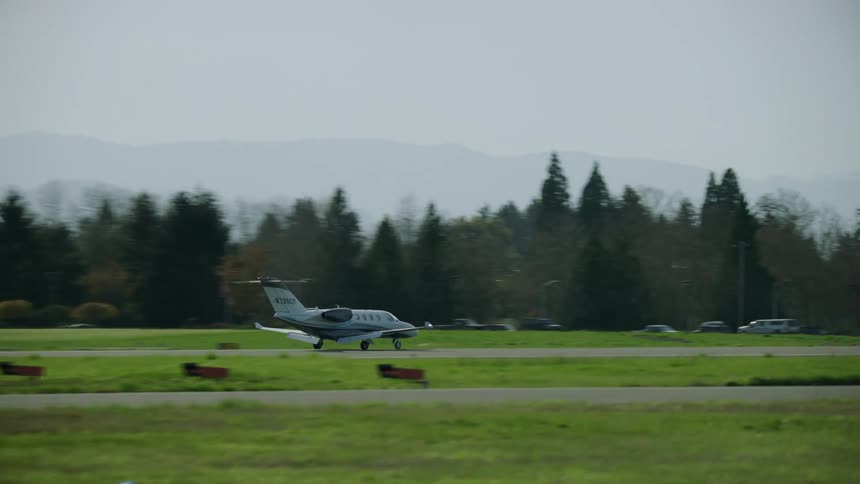 A twin engine private jet lands in spring time at an airport after a private flight across the world