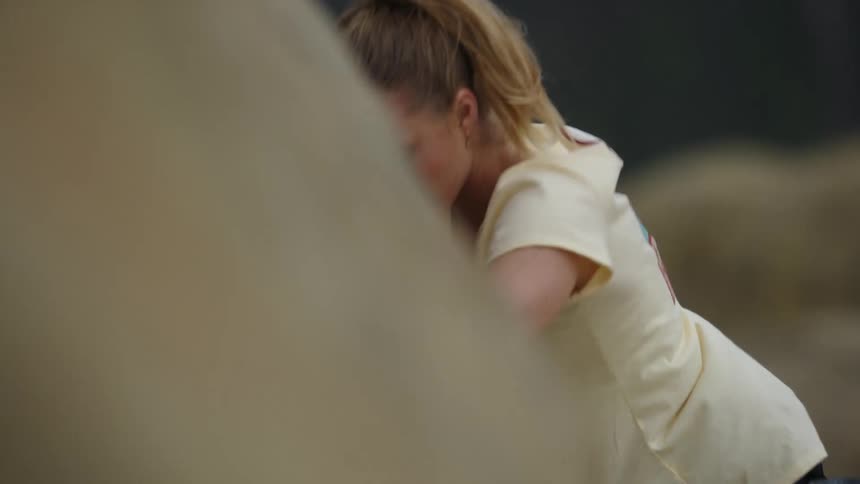A blonde haired woman is climbing up the cliff