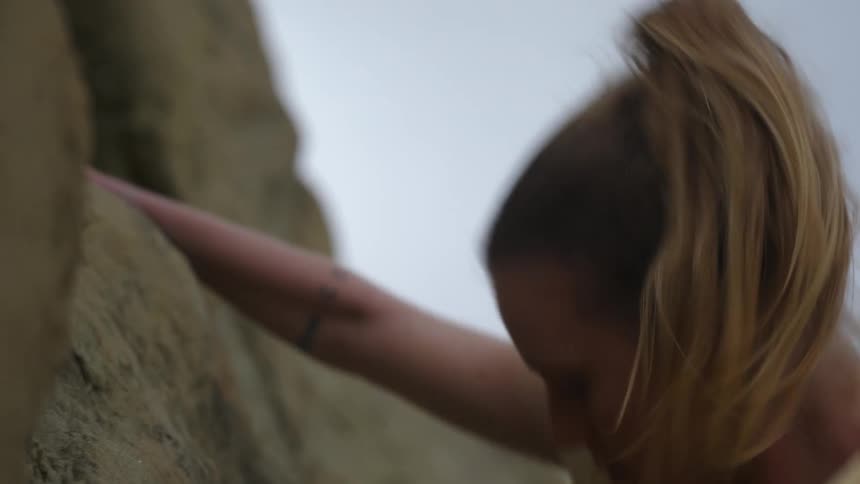 A woman free climbs up a mountain