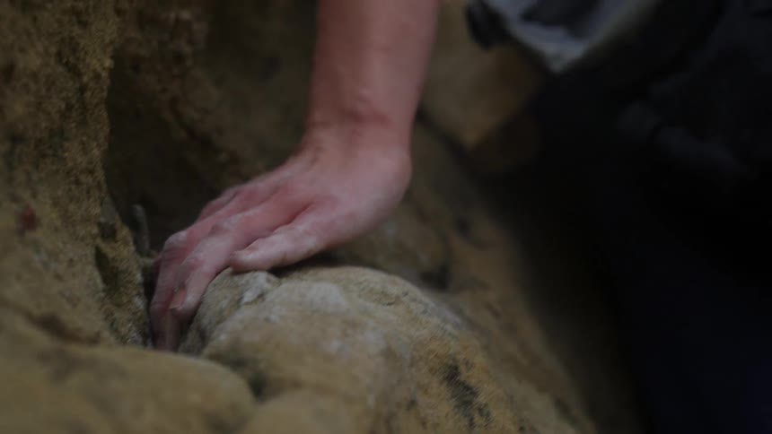A womans hand is covered in chalk as she is rock climbing outdoors