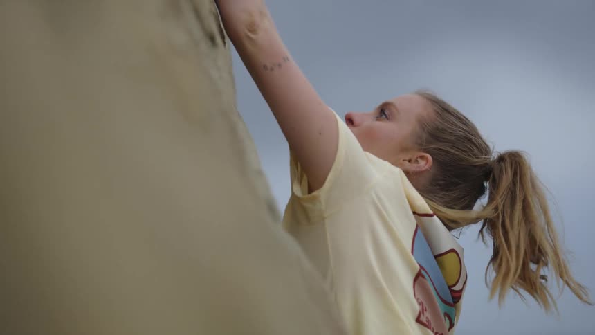 A woman climbs up the side of a mountain