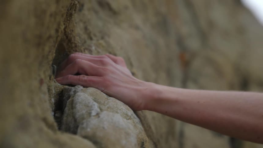 Close up of a young blonde woman climbing a rock wall