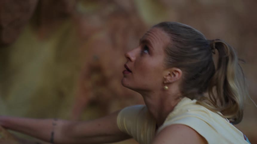 Female rock climber considers the rock wall before reaching for a handhold