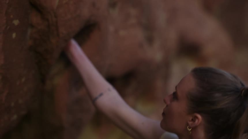 A woman climbs a rock face using her hands