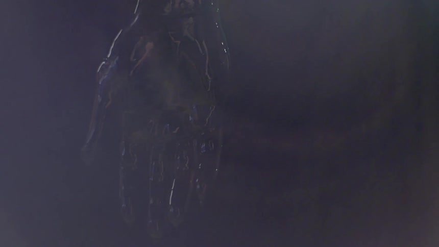 A black reflective hand hangs in the dark