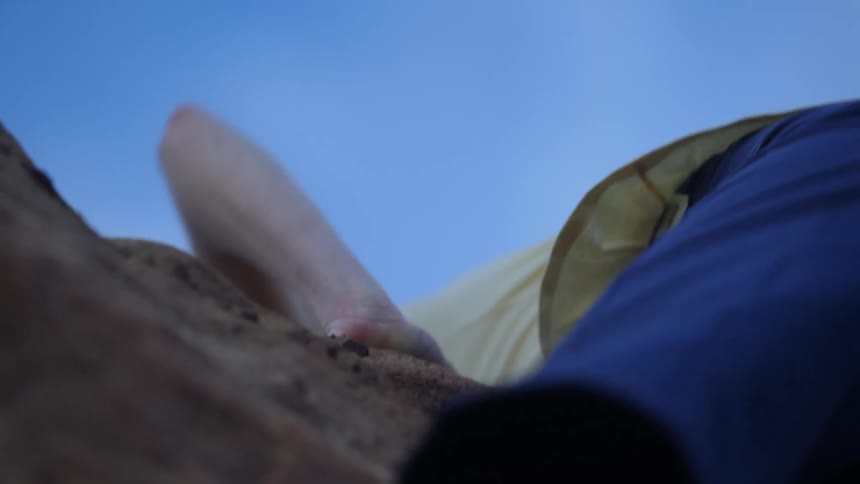 A woman climbs a natural rock face outdoors during the day