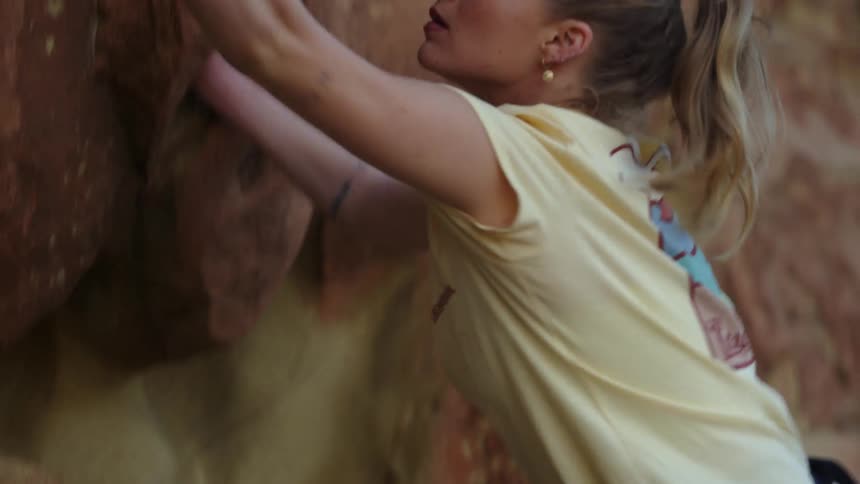 A woman free climbs up the side of a mountain
