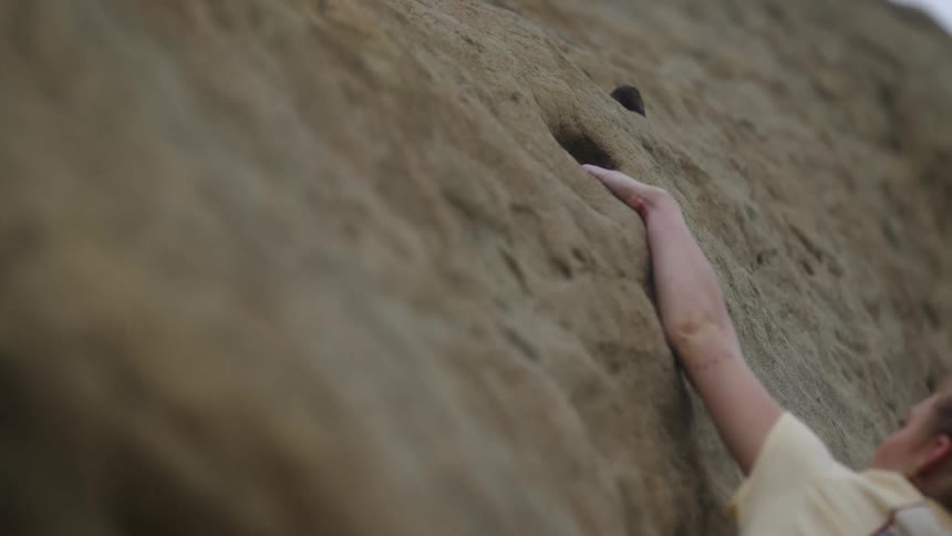Woman climbs cliff wall on windy day