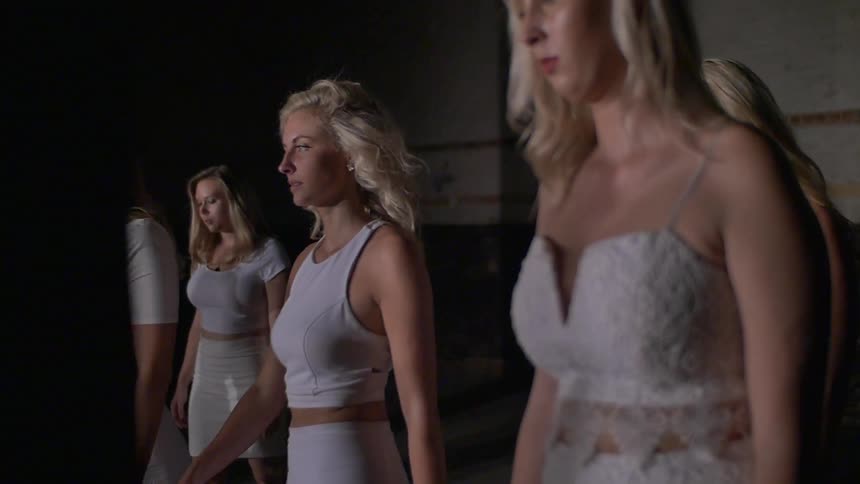 A blonde woman walks past a group of other blonde women