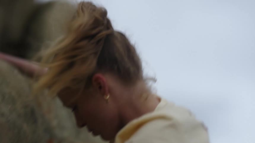 A woman uses her arm strength to pull herself of a cliff as shes rock climbing