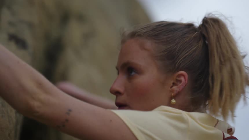 A woman takes a deep breath while climbing up a mountain