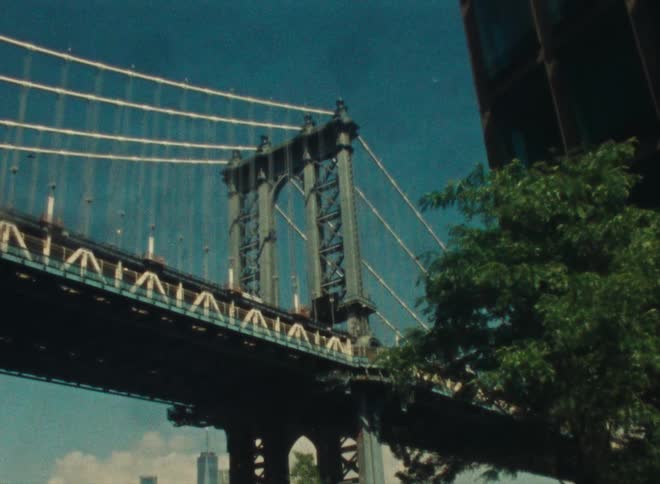 A truck travels across a suspension bridge under a clear blue sky