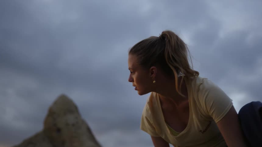 A woman climbing a rocky mountainside at sunset