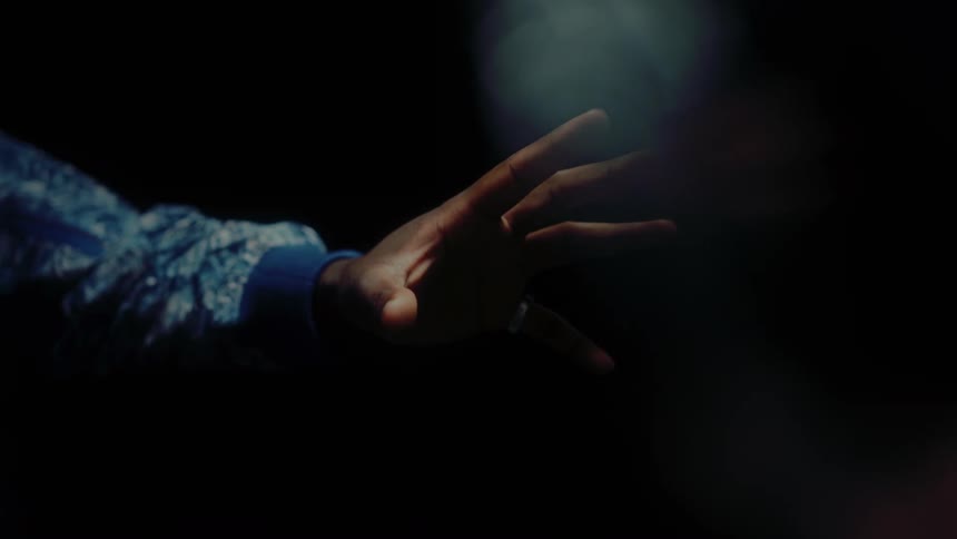 A man reaches his hand out in front of him and moves his fingers