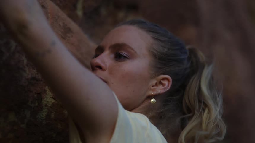 A young female rock climber making her way across a cliffside