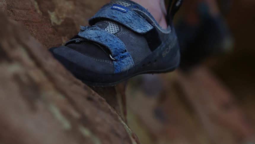 Rock climber pushes with a foot wearing blue footwear