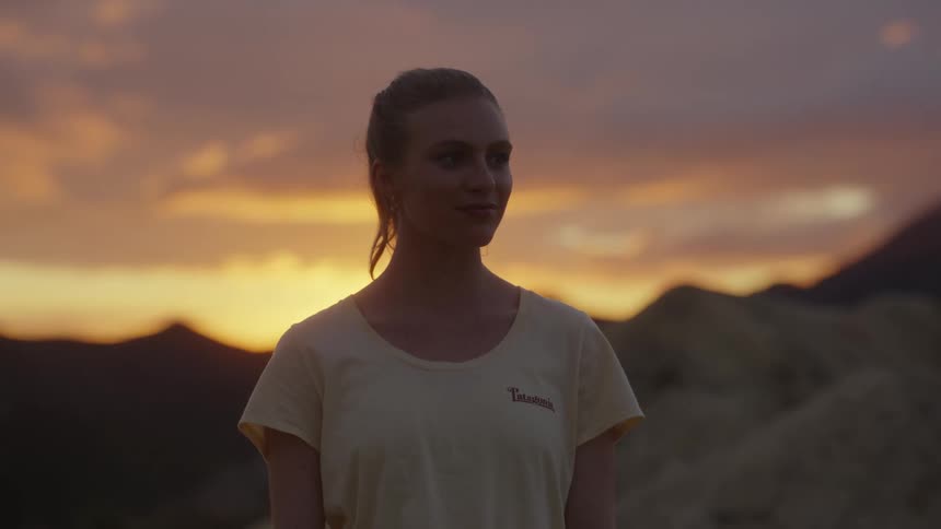 A woman standing in mountains at sunset