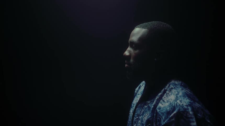Black man stands in the dark and shows his profile