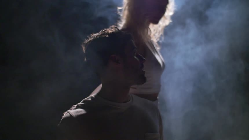 A woman walks over to a sitting man touching his chest