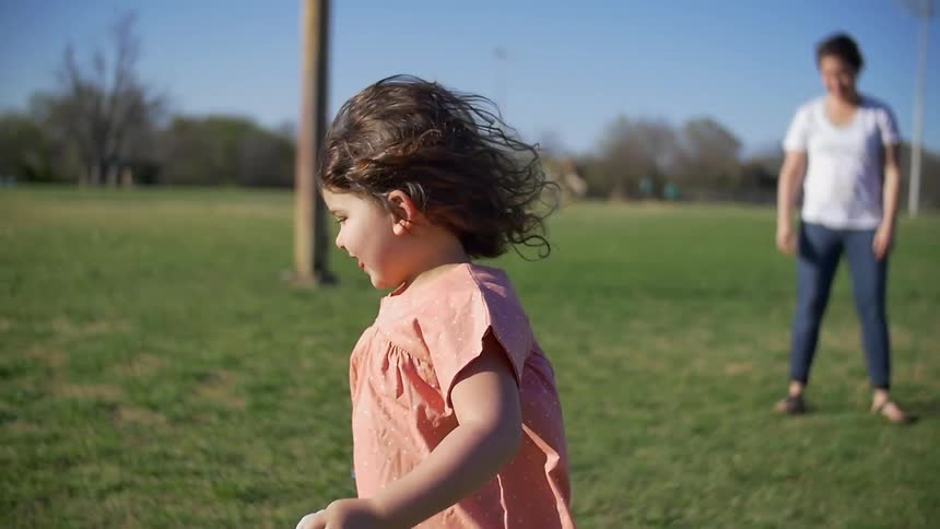 A girl runs across a field as a woman watches