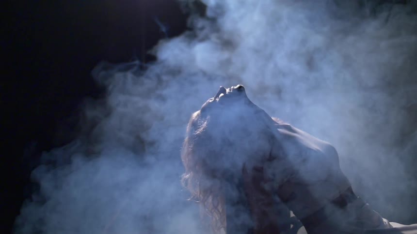 A woman is leaning back in a chair surrounded by smoke