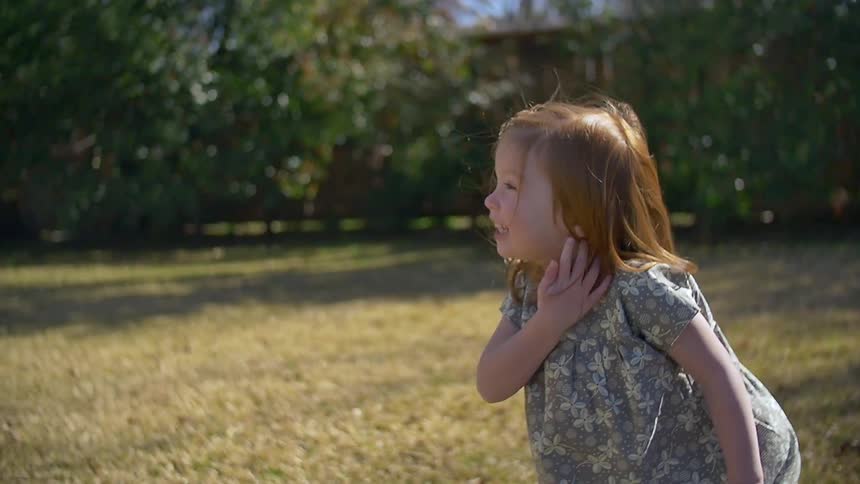 A child laughs near some grass on a sunny day