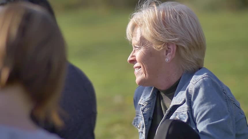Women sit down on the grass smiling