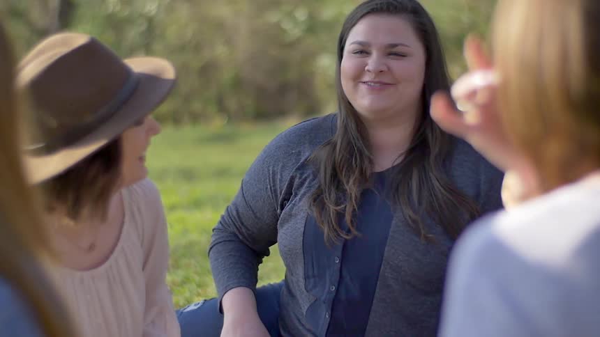 Women talk and laugh while sitting on the grass