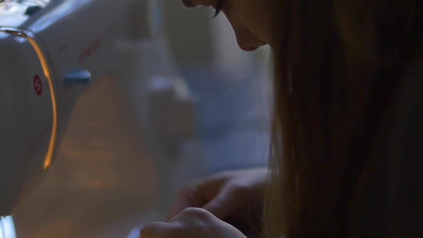 A woman is sewing fabric near a machine