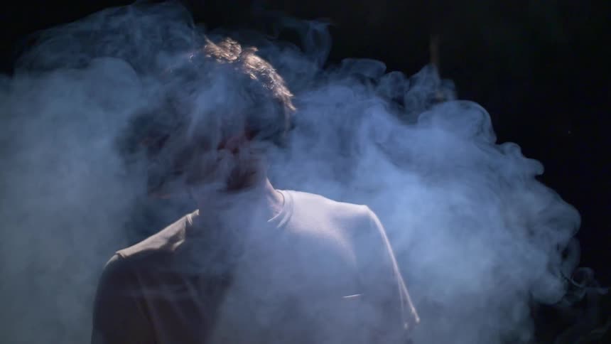 A man is slowly surrounded by smoke
