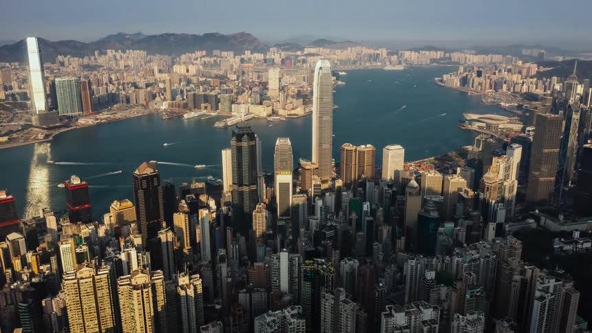 A time lapse from an aerial view of boats in a waterway with high rise office buildings on both sides