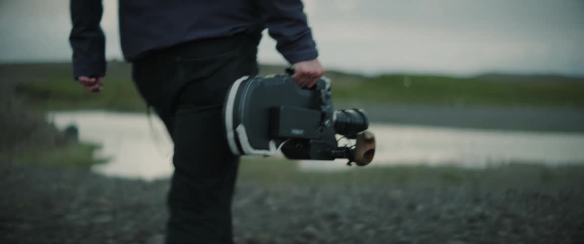 A person is holding some camera around the nature area