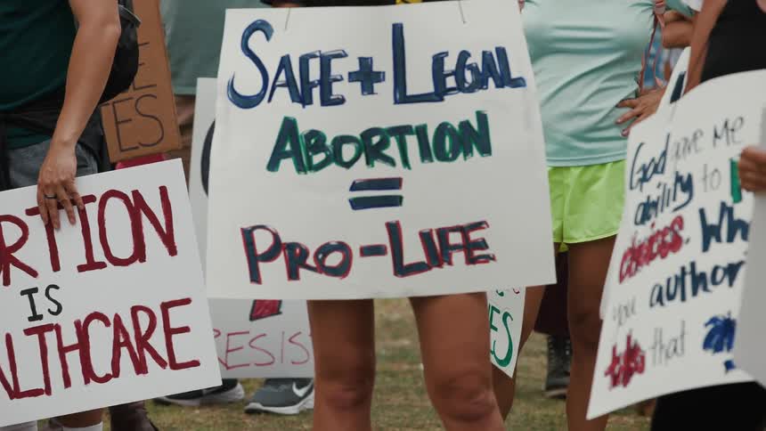 A group of women are outside holding signs at an rally